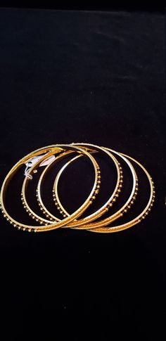 "* Handcrafted Gold Plated 4 Bangle Set. Sold as a set. * Bangles with pretty black beads and gold beads * High Quality 22 K Gold Plated- 4 Bangle set * Size 2.6 has 2.40\" inner circle diameter; Size 2.8 has 2.52\" inner circle diameter Gorgeous gold-plated bangle/ bracelet best exemplifies the careful craftsmanship done on it -- a specialty at Nemali Jewelry. It has a special tone of elegance attached to it. The intricate handmade design of the bangle/bracelet set gives it a fresh and original Gold Beaded Bangle Jewelry, Gold Stackable Bracelets For Festivals, Traditional Gold Beaded Round Bracelets, Gold Bangle With Round Beads For Wedding, Gold Festive Bangle, Black Beads Bangles, Beads Bangles, Wedding Bangles, Kundan Bangles