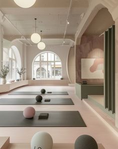 yoga mats and balls in a large room with arched windows on either side of the room