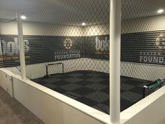 an indoor court with black and white tiles on the wall, surrounded by metal fencing