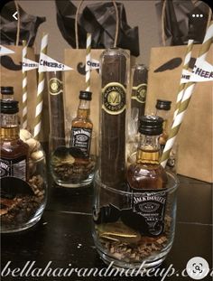 three bottles of whiskey sitting on top of a table next to paper bags with straws in them