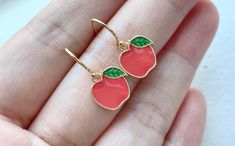 These red / green apple earrings are dainty and kawaii. They are made of the followings: (1) Gold plated enamel apple charm (10 x 11 mm) (2) Gold plated or 14KGF earring hooks ✏️ Please choose your desired color of apple charm ✏️ Please choose your desired plating of earring hooks 🍎 NECKLACE 🍏 → https://www.etsy.com/listing/1026344723 【BEFORE PURCHASE, PLEASE NOTE THE FOLLOWINGS】 ☆ VAT, GST and any other taxes from your country are NOT included in the listing price. Buyers are responsible for Cute Red Round Jewelry, Cute Round Red Jewelry, Handmade Red Kawaii Jewelry, Cute Red Earrings With Fruit Design, Cute Cherry-colored Jewelry For Gifts, Cute Cherry-colored Jewelry Gift, Cute Red Enamel Earrings, Cute Handmade Cherry Jewelry, Cute Fruit Design Jewelry For Gifts