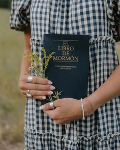 a woman holding a book in her hands and flowers on the other side of her body