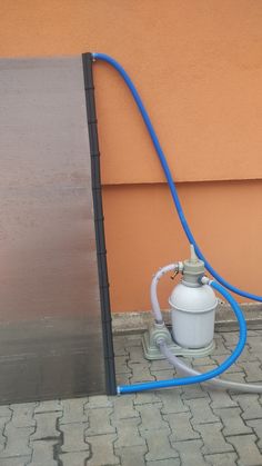 a blue hose connected to a white fire hydrant on the side of a building