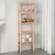 a wooden shelf filled with containers next to a white bath tub and shower curtain in a bathroom