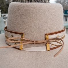 We love what can be done with any type of materials our design team finds. Take a look at this zipper and gold tile hatband. The band is 22.5" x 1.5" and has adjustable tan ties in the back so it can fit hats from 22.5-34". The bottom layer is a soft sorrel brown leather that has been topped with a tan and gold zipper. The zipper runs the entire length of the hatband and really compliments the gold swarvokski tiles that have been added. Something you can wear on your hat every day and we know pe Adjustable Beige Hat Band For Rodeo, Adjustable Beige Hat Band With Flat Brim, Beige Adjustable Flat Brim Hat Bands, Adjustable Beige Flat Brim Hat Band, Adjustable Brimmed Gold Hat, Gold Bohemian Hat Band For Rodeo, Adjustable Gold Western Hat, Adjustable Brown Hat Band For Flat Crown, Adjustable Gold Hats For Rodeo