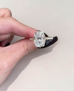 a woman's hand holding an engagement ring with two diamonds on it and the middle finger