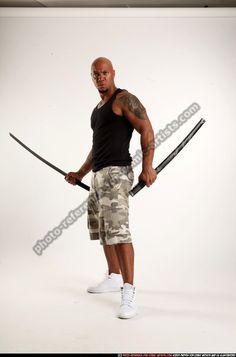 a man holding two swords in one hand and posing for the camera with his other