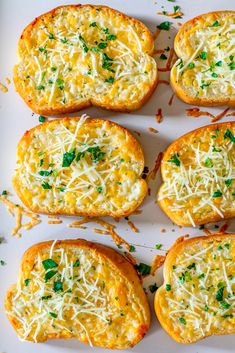 several pieces of bread with cheese and parmesan on top sitting on a white plate