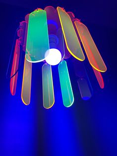 a multicolored light fixture in the dark with blue and purple lighting behind it