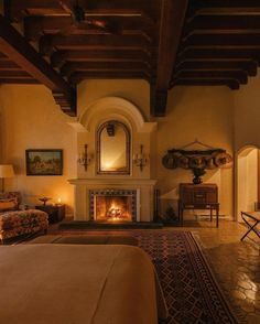 a bedroom with a fireplace, couch and chair in front of the bed is lit by candles