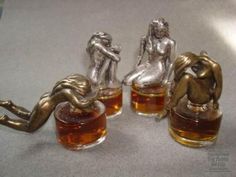 three silver figurines sitting on top of each other next to some whiskey glasses