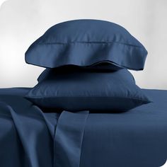 two pillows and one pillow on top of each other with blue sheets in the background