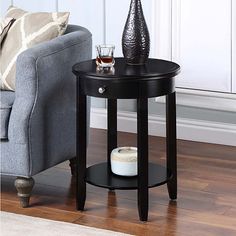 a black end table with a vase and candle on it in front of a couch