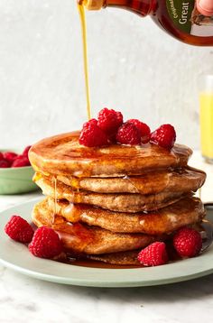 a stack of pancakes with syrup and raspberries