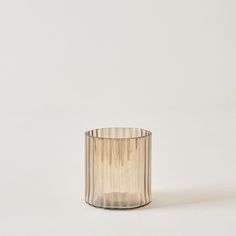 a small glass candle holder on a white surface with the light reflecting off it's side