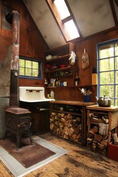 a wood stove sitting inside of a kitchen next to a pile of firewood on top of a hard wood floor