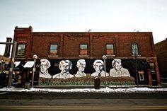 a large mural on the side of a building with people's faces painted on it