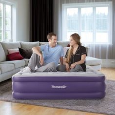 a man and woman sitting on top of an inflatable mattress