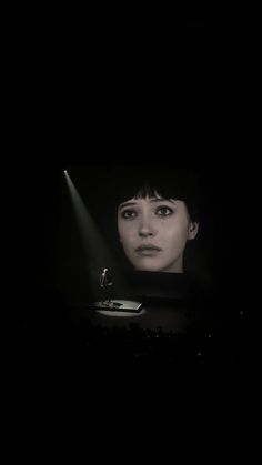 a woman in the dark looking at her cell phone and light coming from behind her