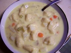 a bowl of soup with meat and vegetables in it on a table next to a spoon