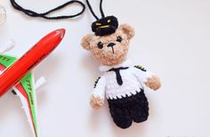 a teddy bear wearing a sailor's outfit next to an airplane and a crochet pen holder