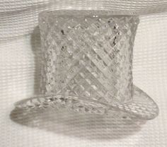 a clear glass hat sitting on top of a white cloth