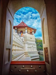 an arch leading to a white building with a red roof and flag on it's side