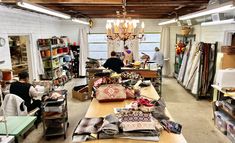 a room filled with lots of different types of cloths and fabrics on tables in front of windows