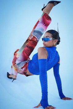 a woman in blue is doing a handstand on one leg while wearing sunglasses