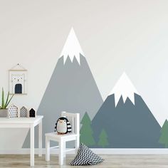 a white table and chair in front of a wall with mountains painted on the side