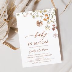 the baby in bloom card is next to feathers