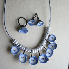 a necklace and earring set with blue flowers on white bead, black cord