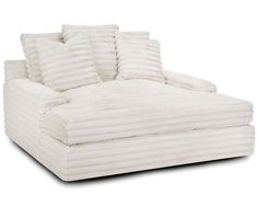 a white couch with five pillows on it's back and one arm facing the camera