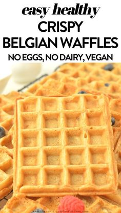 two waffles with blueberries and raspberries on top are shown in front of the words easy healthy crispy belgian waffles no eggs, no dairy vegan