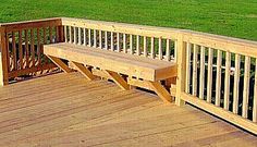 a wooden bench sitting on top of a wooden deck next to a lush green field