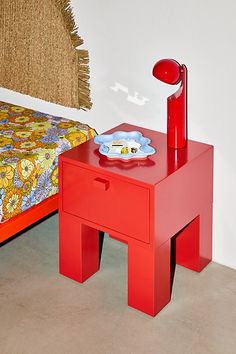 a red table with a plate on it next to a bed