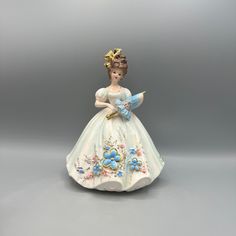 a porcelain figurine of a woman in a white dress with blue flowers on it