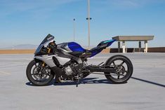 a blue and black motorcycle is parked in an empty parking lot next to a bench