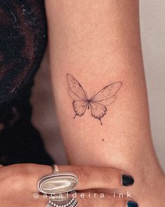 a woman's arm with a small butterfly tattoo on the left side of her wrist