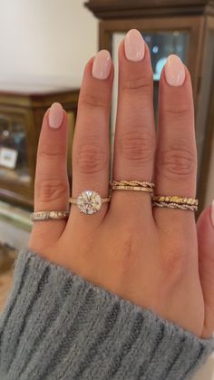 a woman's hand with three different rings on her fingers and one ring in the middle