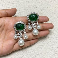 Emerald Pearl Diamond Earrings feature dark green stones accented by sparkling CZ diamonds and elegant white pearls.  The statement dangle design offers a blend of modern sophistication and timeless elegance, making them perfect for a bride on her wedding day. These earrings are an exquisite gift, adding luxury and beauty to any bridal ensemble. *𝐏𝐑𝐎𝐃𝐔𝐂𝐓 𝐃𝐄𝐓𝐀𝐈𝐋* * 𝐌𝐚𝐭𝐞𝐫𝐢𝐚𝐥: Brass * 𝐏𝐥𝐚𝐭𝐢𝐧𝐠: White Rhodium Plated * 𝐒𝐭𝐨𝐧𝐞: AAA-quality CZ Diamond & Emerald. *𝐃𝐈𝐌𝐄 Elegant Green Jeweled Bridal Earrings, Green Pearl Earrings For Wedding, Green Teardrop Pearl Earrings For Wedding, Heavy Jewellery, Green Stone Earrings, Bride Wedding Gift, Wedding Gifts For Bride, Green Stones, Pearl And Diamond Earrings