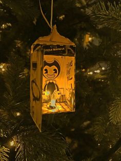 an ornament hanging from a christmas tree in the shape of a box with a cartoon character on it