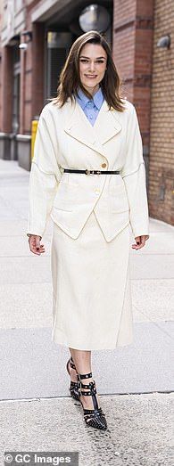 a woman is walking down the street wearing a white coat