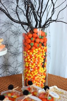 a vase filled with candy sitting on top of a table next to a tree branch