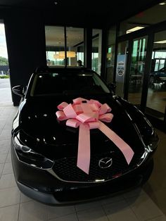 a black car with a pink bow on the hood