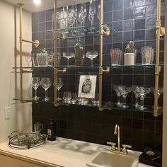 a kitchen counter with wine glasses on the shelves and other glassware in front of it