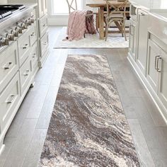 a kitchen with white cabinets and an area rug on the floor