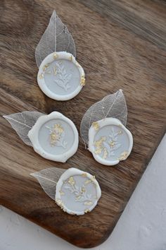 three small plates with leaves on them sitting on a wooden table next to a cutting board