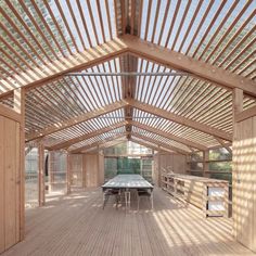 a wooden structure with tables and benches in the center is surrounded by wood slats