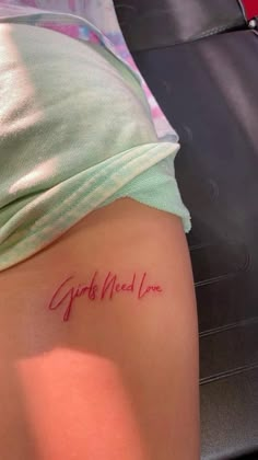 a woman with a tattoo on her thigh that says girls need love in cursive writing